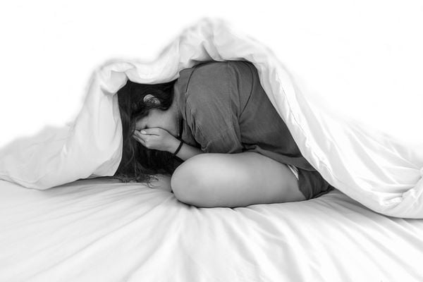 жена, свита на кълбо в легло, покрита със завивка