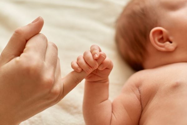 бебе държи пръста на майка си