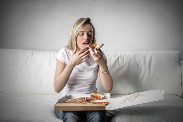 При смяната на часа през пролетта е възможно да изпитвате необичаен силен глад млада руса жена, която яде пица от кутия