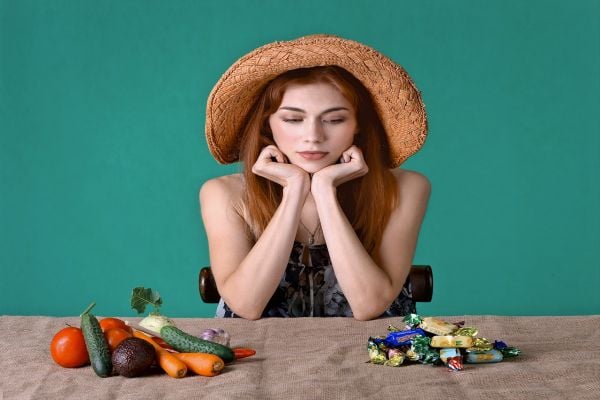 жена стои пред бонбони и зеленчуци