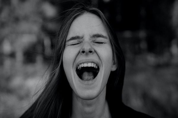 черно-бяла снимка на жена с тъмна коса, която крещи