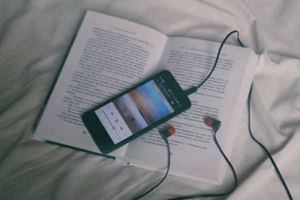книга и мобилен телефон със слушалки