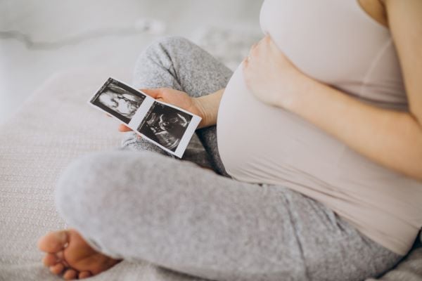 Бременна жена държи ехографска снимка на бебе
