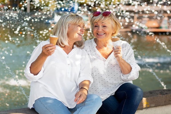 Две усмихнати жени на средна възраст, които държат фунийки сладолед