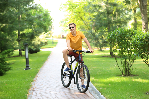 Колоезденето не уврежда простатата млад мъж с оранжева тениска и очила, който кара колело