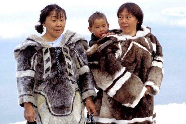 жена и мъж, който държи малко дете, облечени в традиоцинно ескимоско облекло