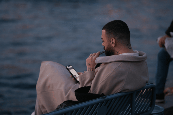 Никотиновите лепенки и дъвки ще ви помогнат да озаптите никотиновия глад, докато отказвате вейпинга мъж, седнал на пейка, който пуши вейп