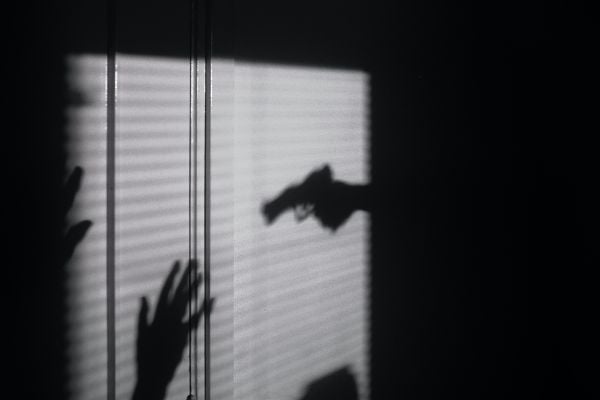 сянка на държащ пистолет, насочен към друг човек