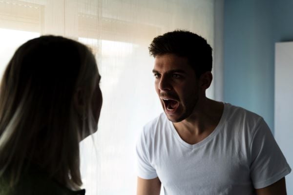 Млад мъж с бяла тениска крещи на жена