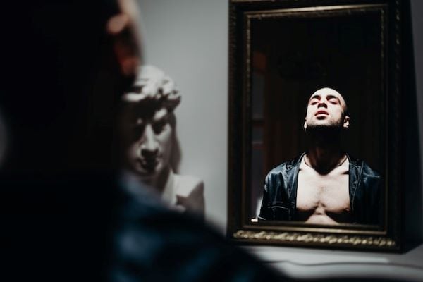 Мъж с разголени гърди, които се гледа в огледало