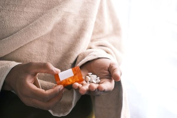 жена изсипва таблетки от оранжево контейнерче