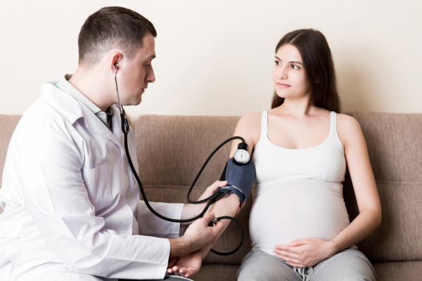 Прееклампсията е опасно заболяване, което засяга жената през бременността лекар, който мери кръвното налягане на бременна жена