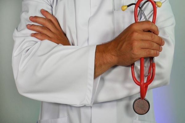 Лекар в бяла престилка държи червен стетоскоп