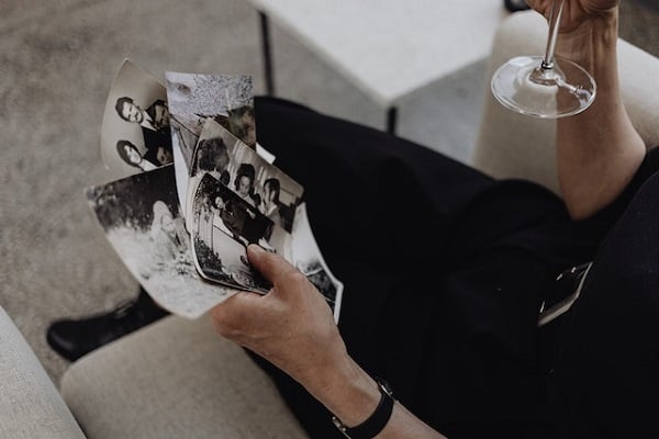 Жена държи чаша и разглежда черно-бели снимки