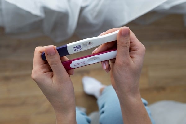 Жена държи два теста за бременност, които показват отрицателен резултат