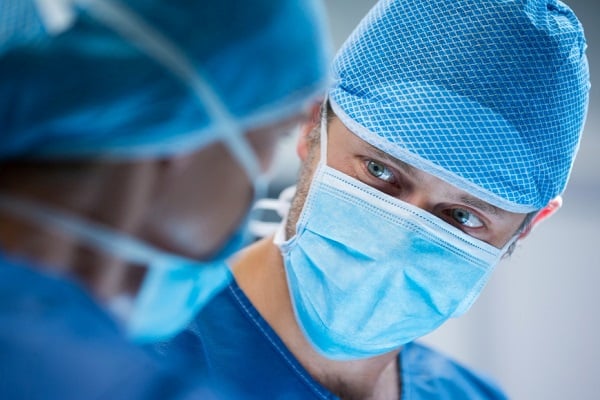 Млад хирург със светли очи в операционна, който гледа свой колега