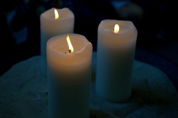 Три бели горящи свещи на тъмен фон