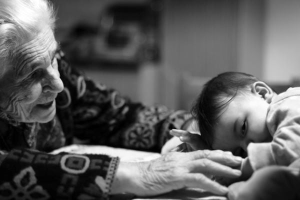 черно-бяла снимка на възрастна жена, която милва бебе