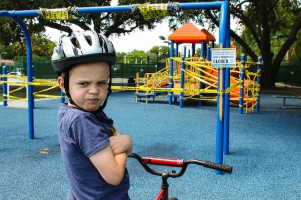 Момче с велосипедна каска и колело, което гледа гневно