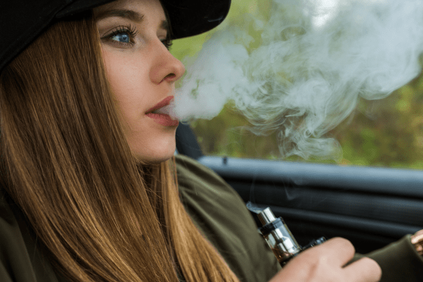 Според специалистите вейпът е по-малко вреден от обикновените цигари млада жена със сини очи, която пуши вейп