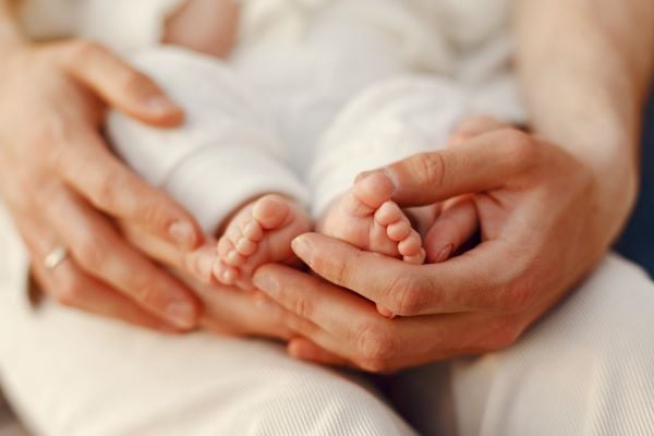 ръце на жена, които държат бебешки крачета