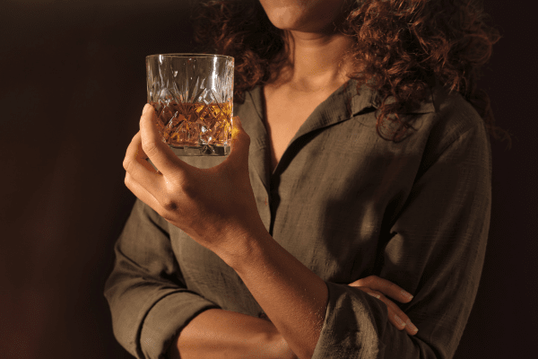 Жените развиват алкохолна зависимост по-бързо от мъжете жена със зелена риза, която държи чаша с алкохол