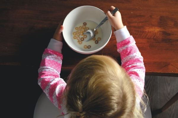 Русо момиченце в гръб яде закуска с прясно мляко