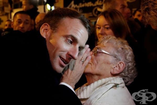 Френският президент Емануел Макрон се опитва да чуе възрастна жена в тълпата.