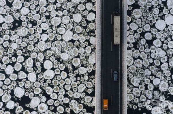 Изглед отгоре на мост над замръзнала вода.